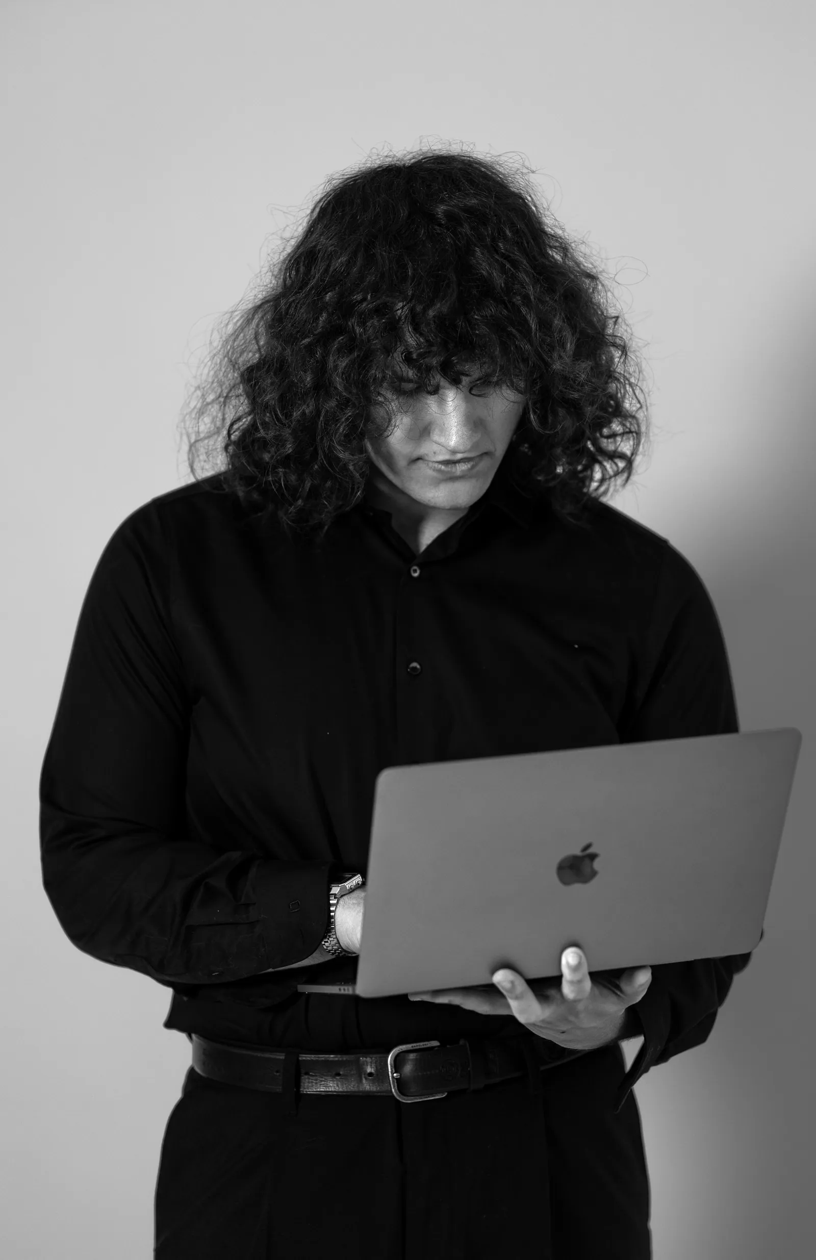 Jeremias Rößner in Schwarz-Weiß, in dunklem Hemd mit einem Laptop in der Hand